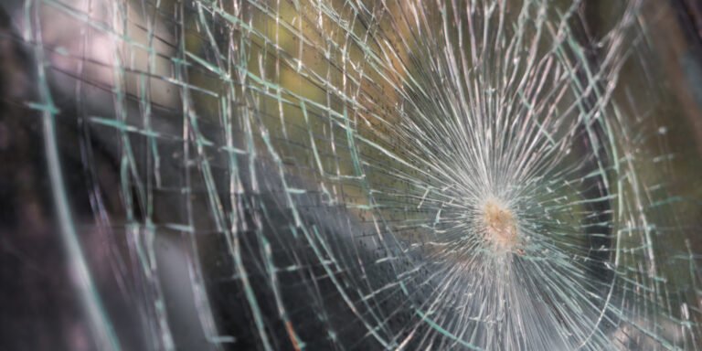 glass broken cracks splinters in front of car . ( filtered image